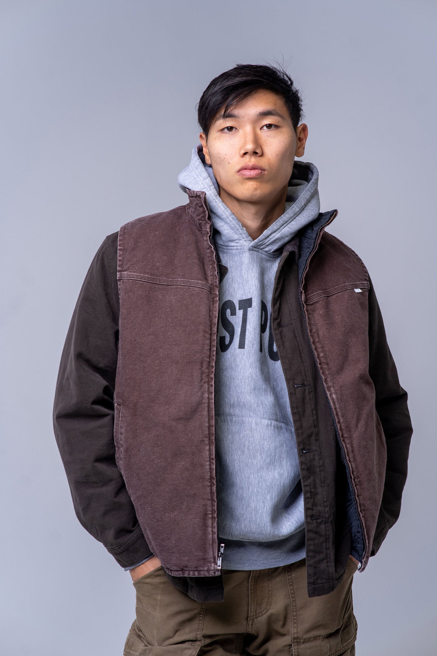 Person wearing a brown vest over a gray hoodie with text on a plain background