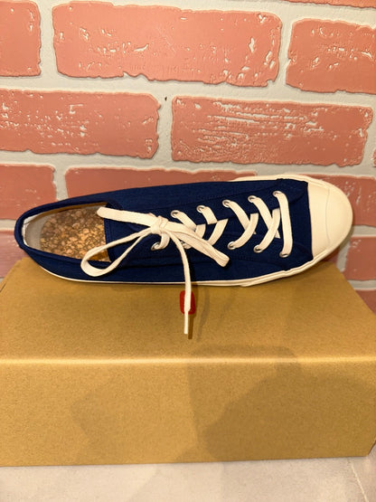 Blue and white sneaker on a cardboard box with a brick wall background