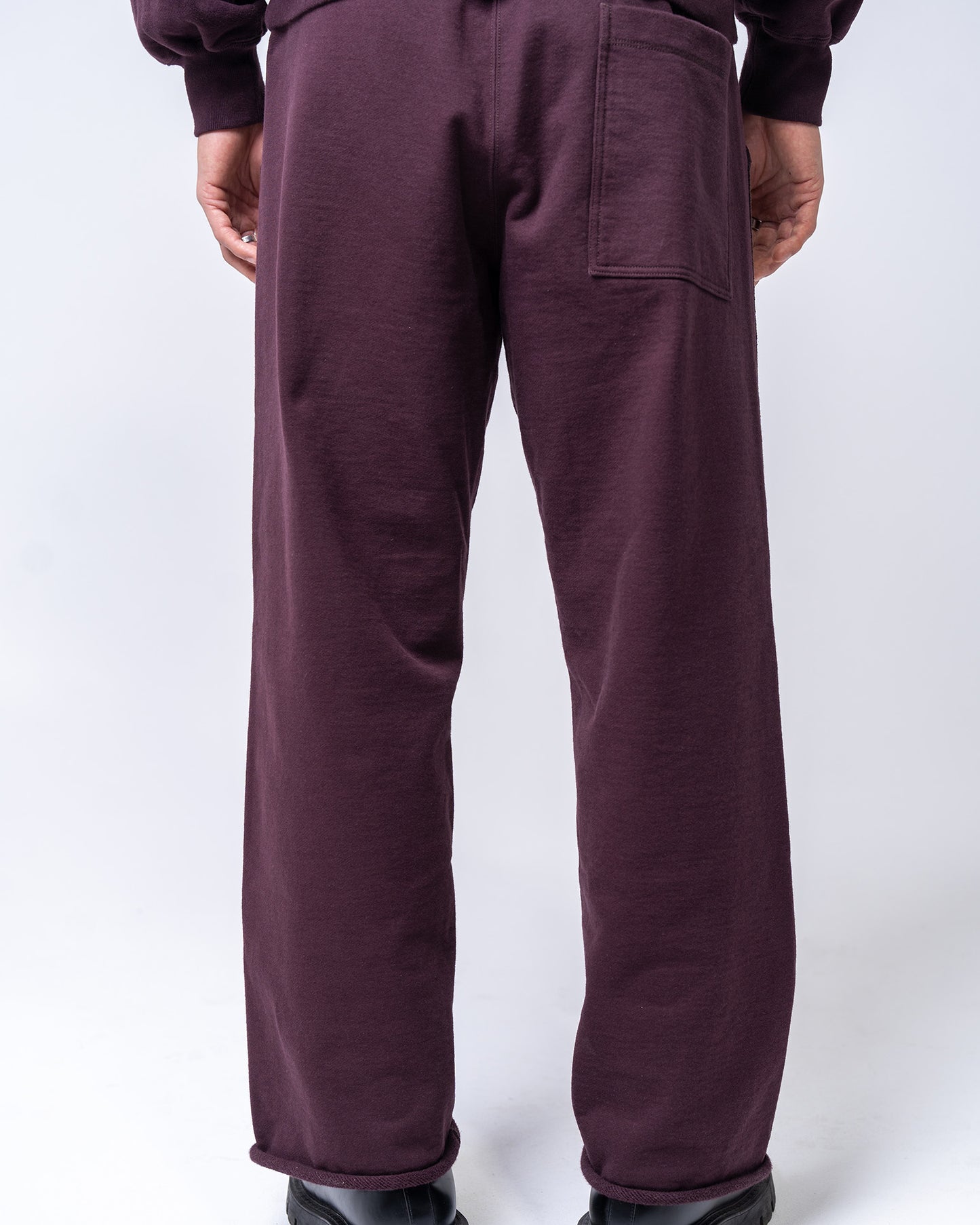 burgundy pants worn by a person on a white background