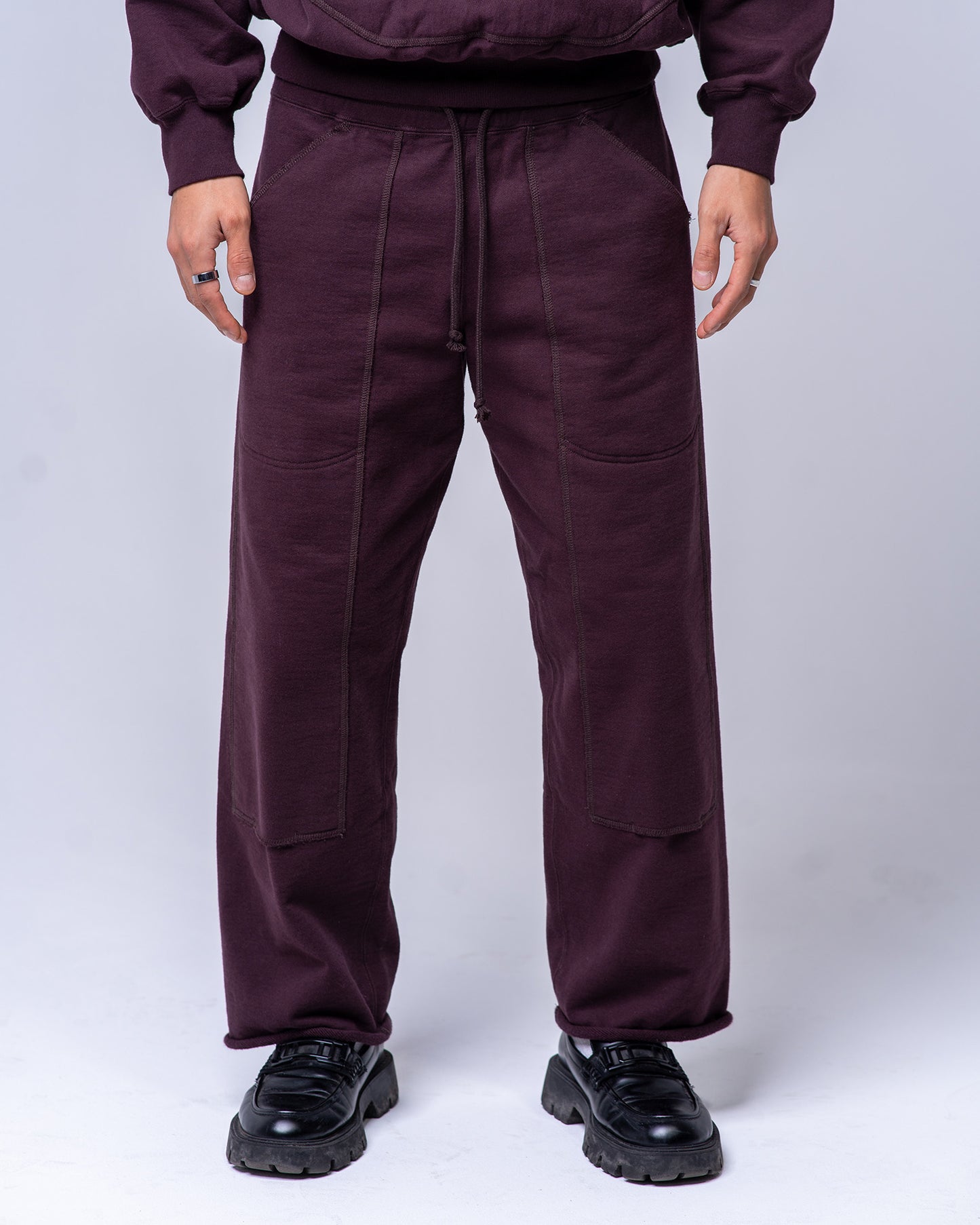 Person wearing a pair of burgundy sweatpants on a white background
