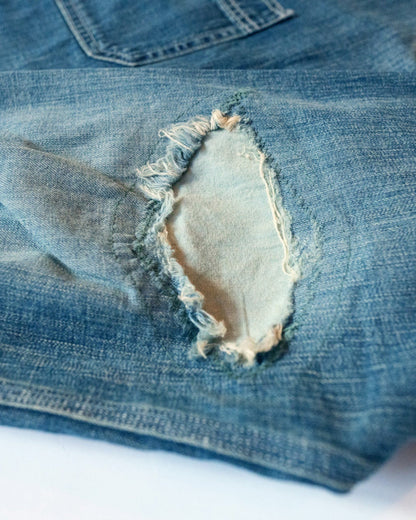 Close-up of a repair of a ripped blue denim shirt elbow with a white background.