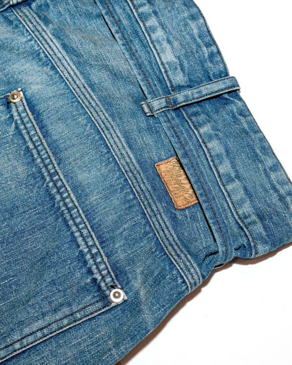 Close-up of blue denim jeans with a brand label on a white background