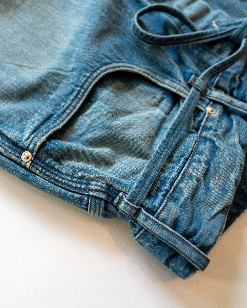 Blue denim pants pocket details on a white background