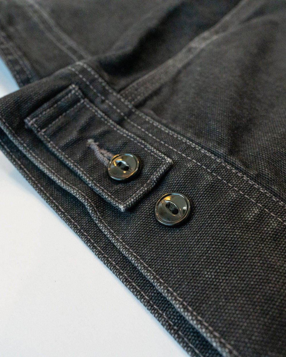 Close-up of a dark denim fabric with buttons on a white background