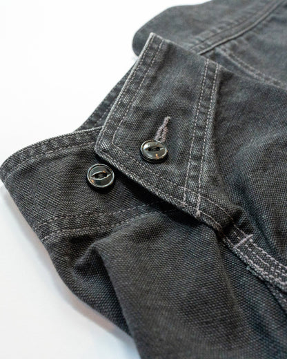 Close-up of dark denim jacket cuff with buttons on a white background