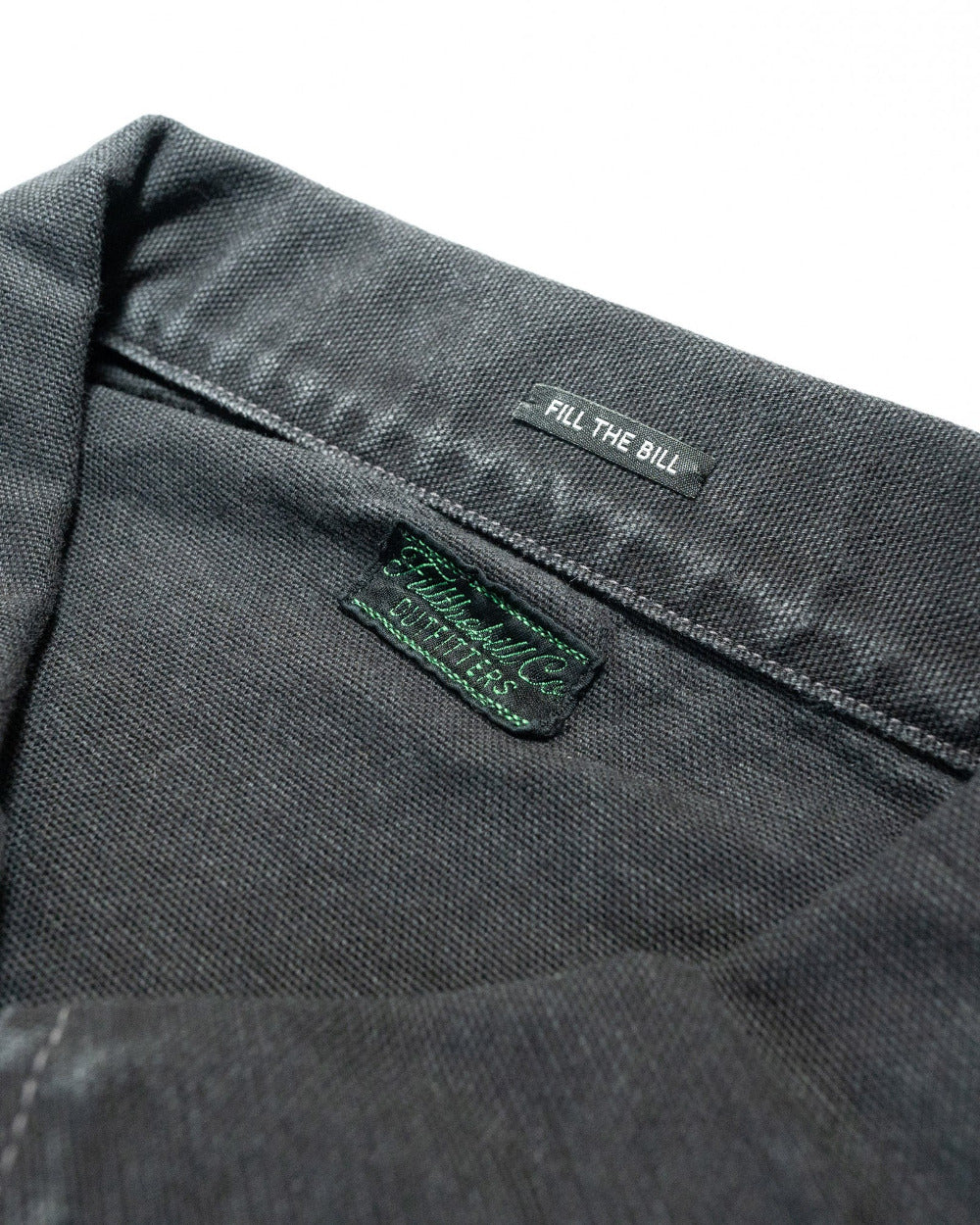 Close-up of a gray fabric with 'Fill The Bill' branding on a white background