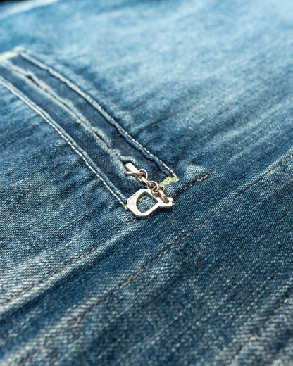 Close-up of a blue denim fabric with a zipper and brand logo.