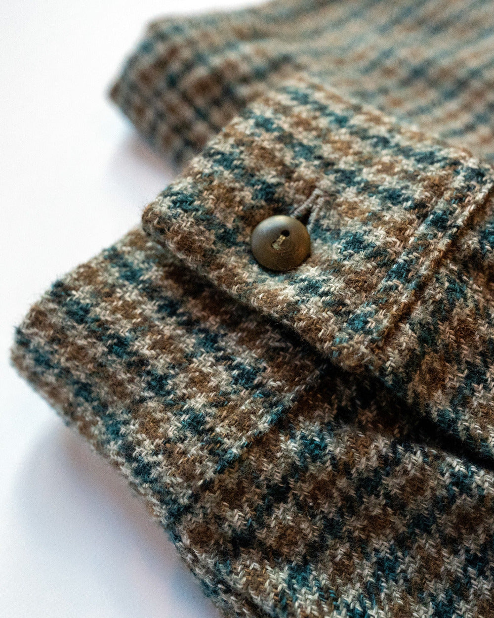 Close-up of a houndstooth fabric cuff with a button on a white background