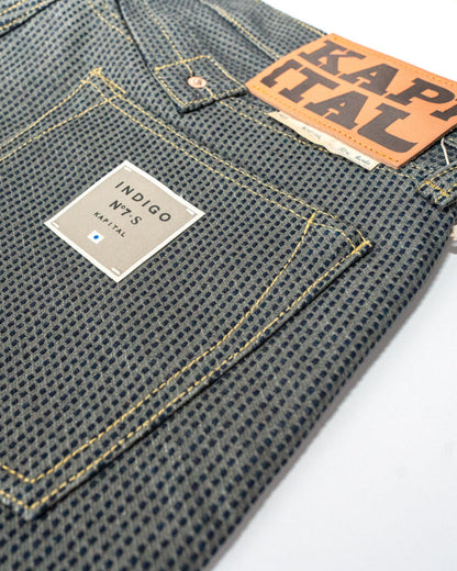 Close-up of denim pants with 'Kapital' labels on a white background.