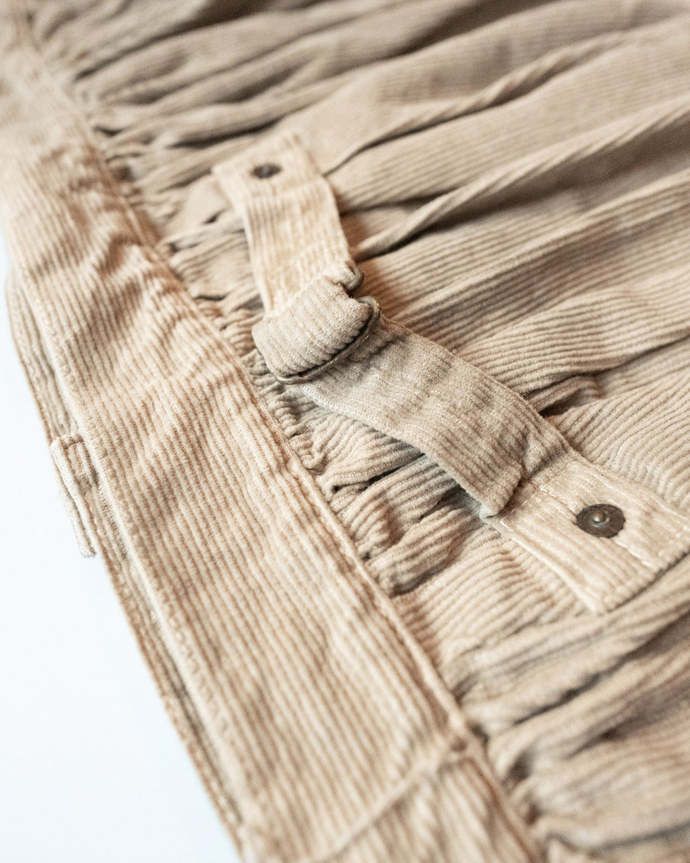 Close-up of beige corduroy fabric with hardware details