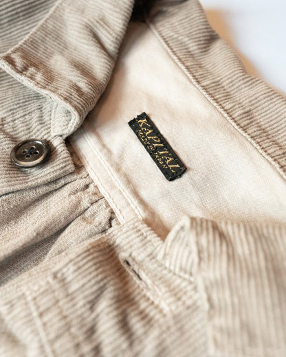 Close-up of a beige corduroy jacket with a kapital brand label on a white background