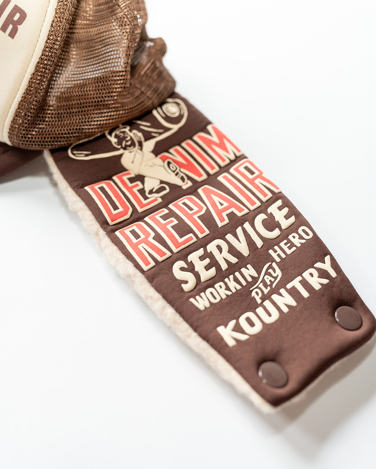 brown flap on a kapital trucker hat with graphics and text 