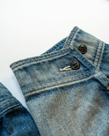 Close-up of blue denim jacket cuff with buttons on a white background