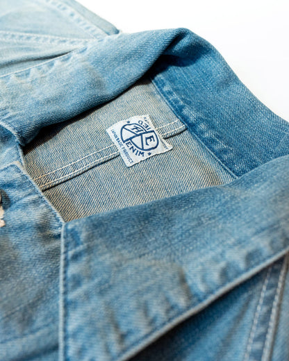 Close-up of a blue denim jacket with a brand logo on a white background