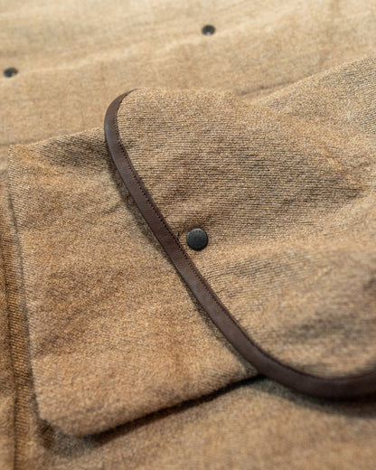 Close-up of a brown textured fabric with a leather strap and button.