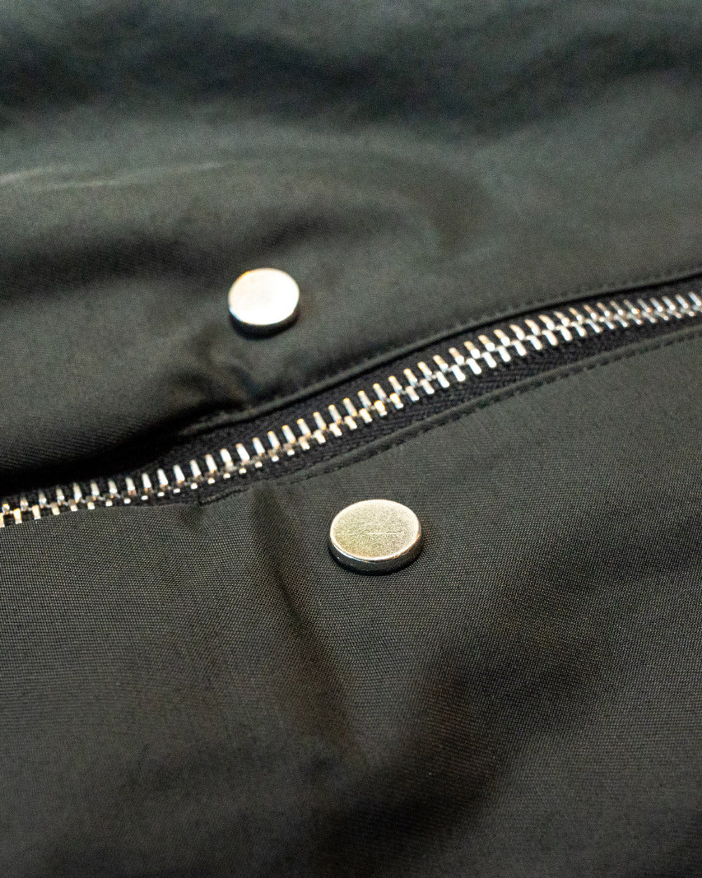 Close-up of a black jacket with a zipper and buttons.