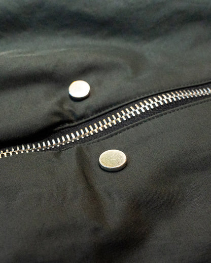 Close-up of a black jacket with a zipper and buttons.