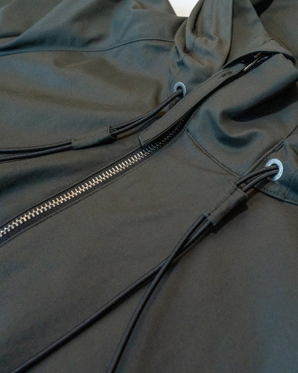Close-up of a dark gray jacket with a zipper and drawstrings.